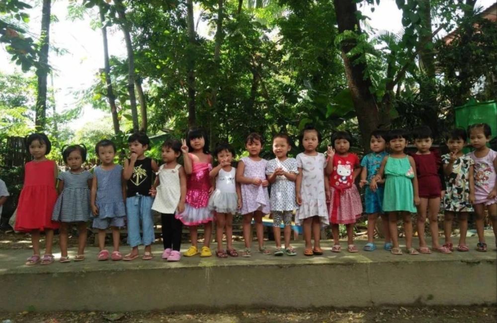 young children standing in a line waving